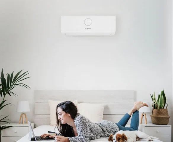 A woman lying in a bedroom with an AC unit.